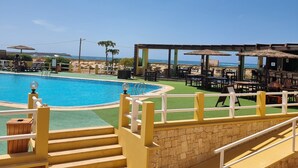 Et privat poolområde med frit kig til havet, et overdækket opholdsområde og en trappe ned til poolen.