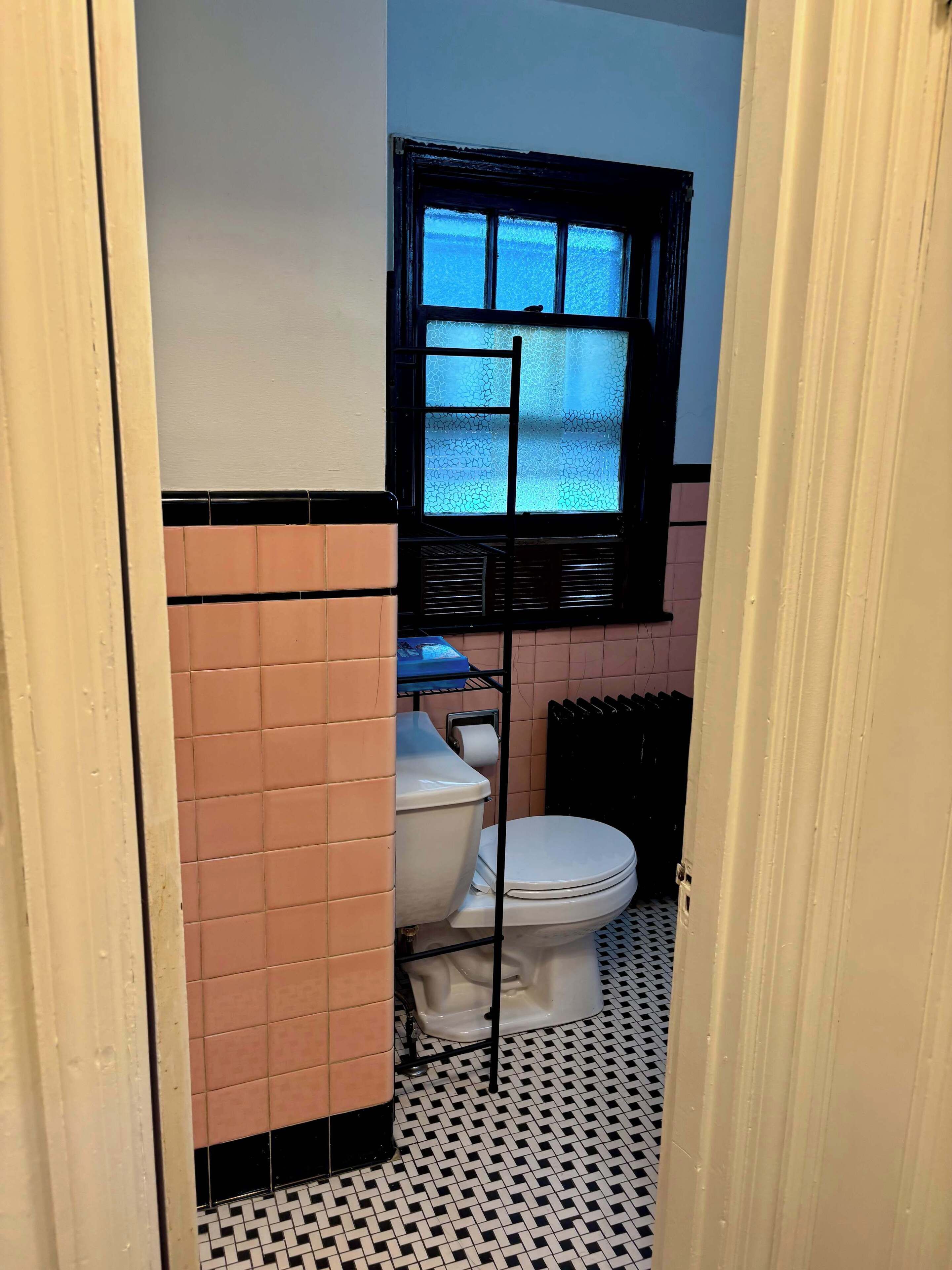 Pieni kylpyhuone, jossa on wc, ikkuna ja patteri.
