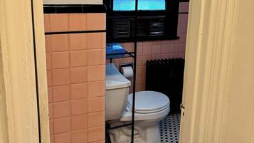 Pieni kylpyhuone, jossa on wc, ikkuna ja patteri.