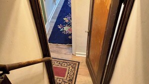 Eine Treppe führt zu einem Flur mit einer Holztür und einem Teppich mit floralem Muster.