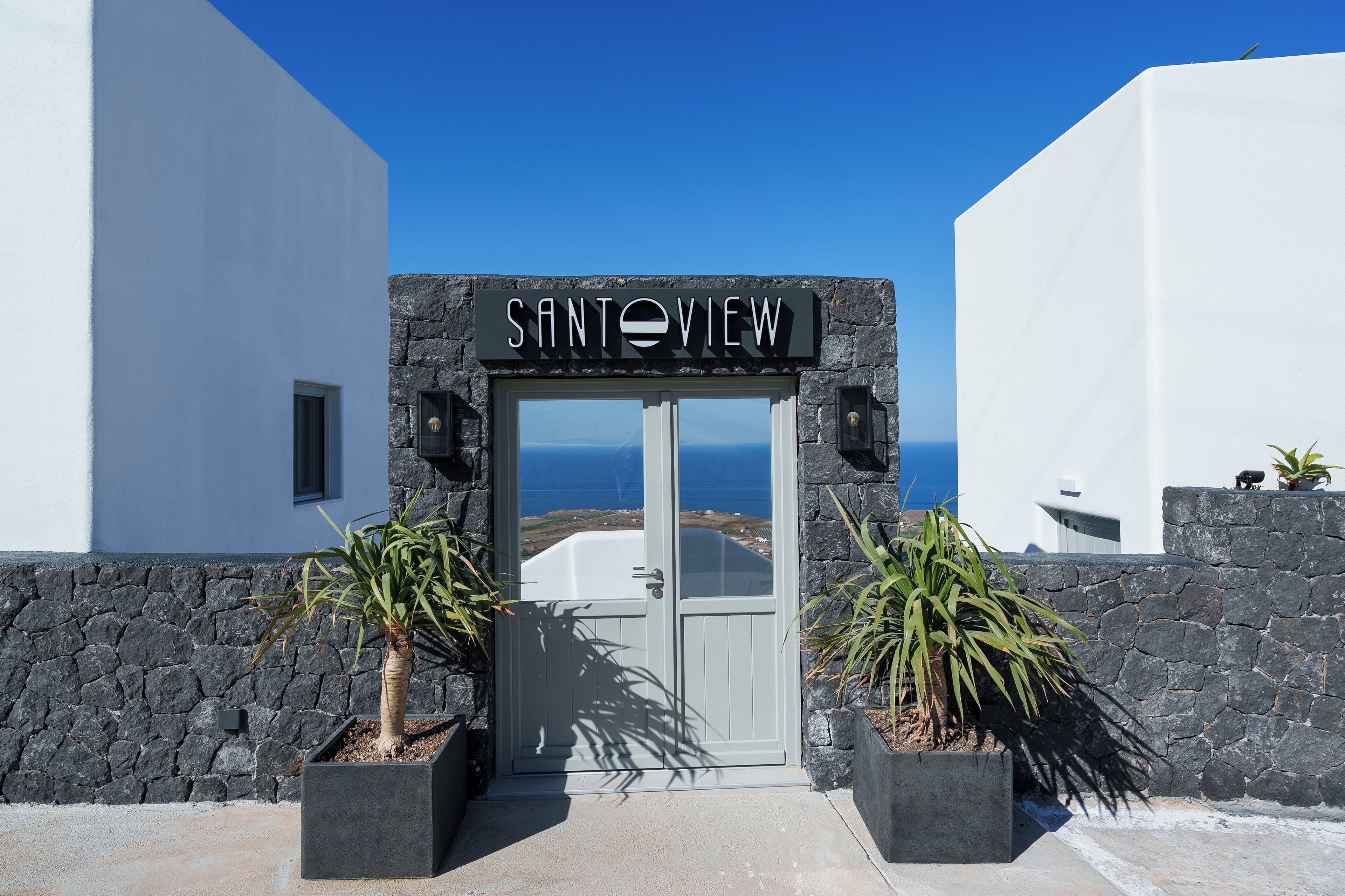A building entrance with a sign reading "SANTOVIEW" and a view of the sea.