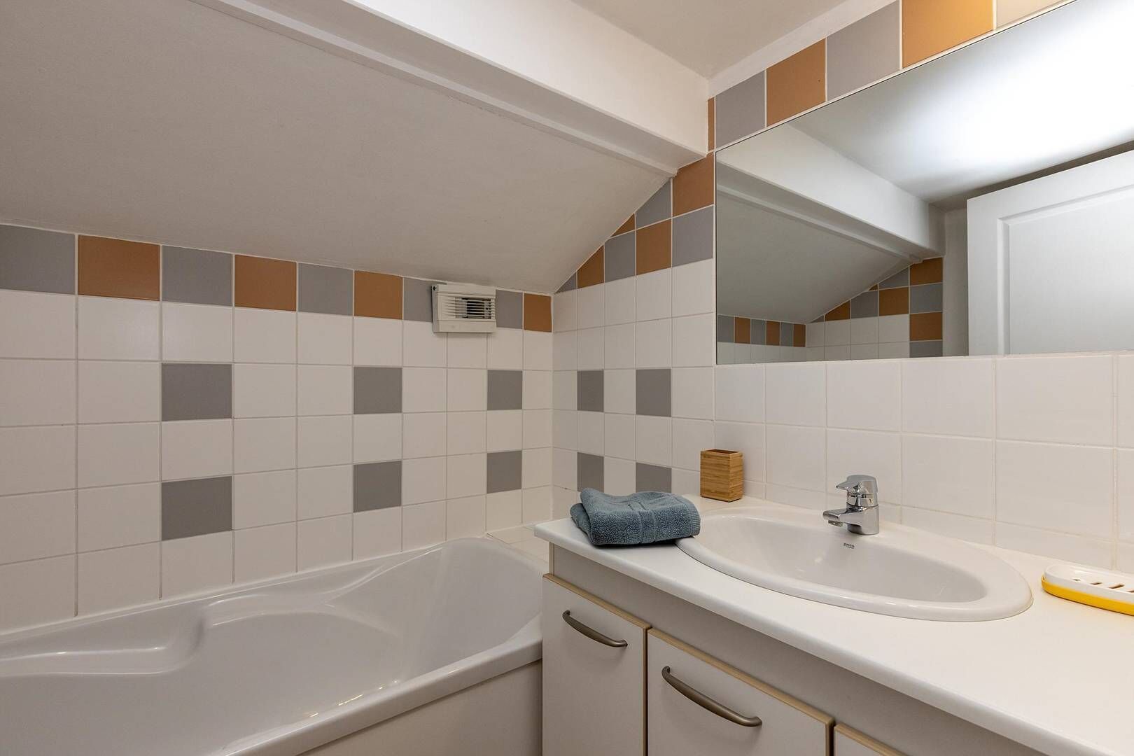 A bathroom with a bathtub, a sink, and a mirror.