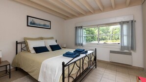 A bedroom with a bed, a window with curtains, a radiator, and a painting on the wall. - Villa Cormoran (MOLIETS ET MAA)