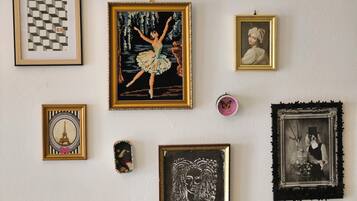 A wall with various framed artworks including a ballet dancer, a checkered pattern, and a portrait.
