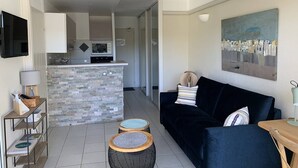A modern living room with a black sofa, a small wooden table, and a stone fireplace. - Résidence du Golf 223 - Moliets (MOLIETS ET MAA)