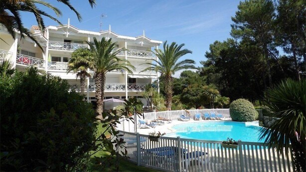 A multi-story hotel with a pool area, surrounded by palm trees and other greenery. - Résidence du Golf 223 - Moliets (MOLIETS ET MAA)