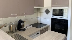 A modern kitchen with grey cabinets, a black stove, a microwave, and a built-in oven. - Résidence du Golf 223 - Moliets (MOLIETS ET MAA)