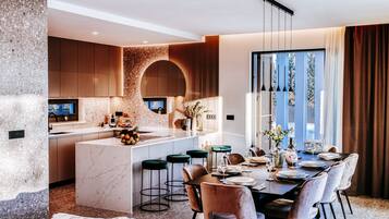 Una cocina moderna con una isla central, taburetes de bar y un comedor con mesa dispuesta para seis personas.