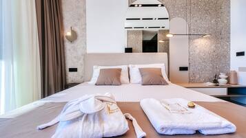 Habitación de hotel con una cama grande, dos toallas, una bata y una mesita de noche con lámpara.