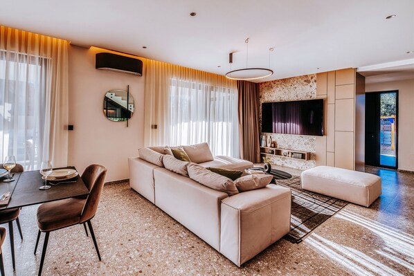 A modern living room with a sofa, a dining table, and a TV. - Villa Javori Zadarvillas (Bibinje)