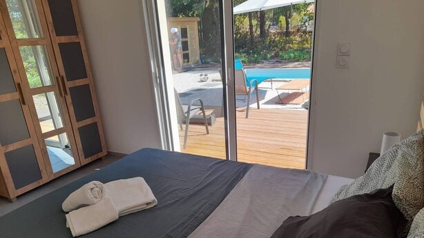 Ein Schlafzimmer mit einem großen Bett, einem Holzschrank und Blick auf einen Außenpool.