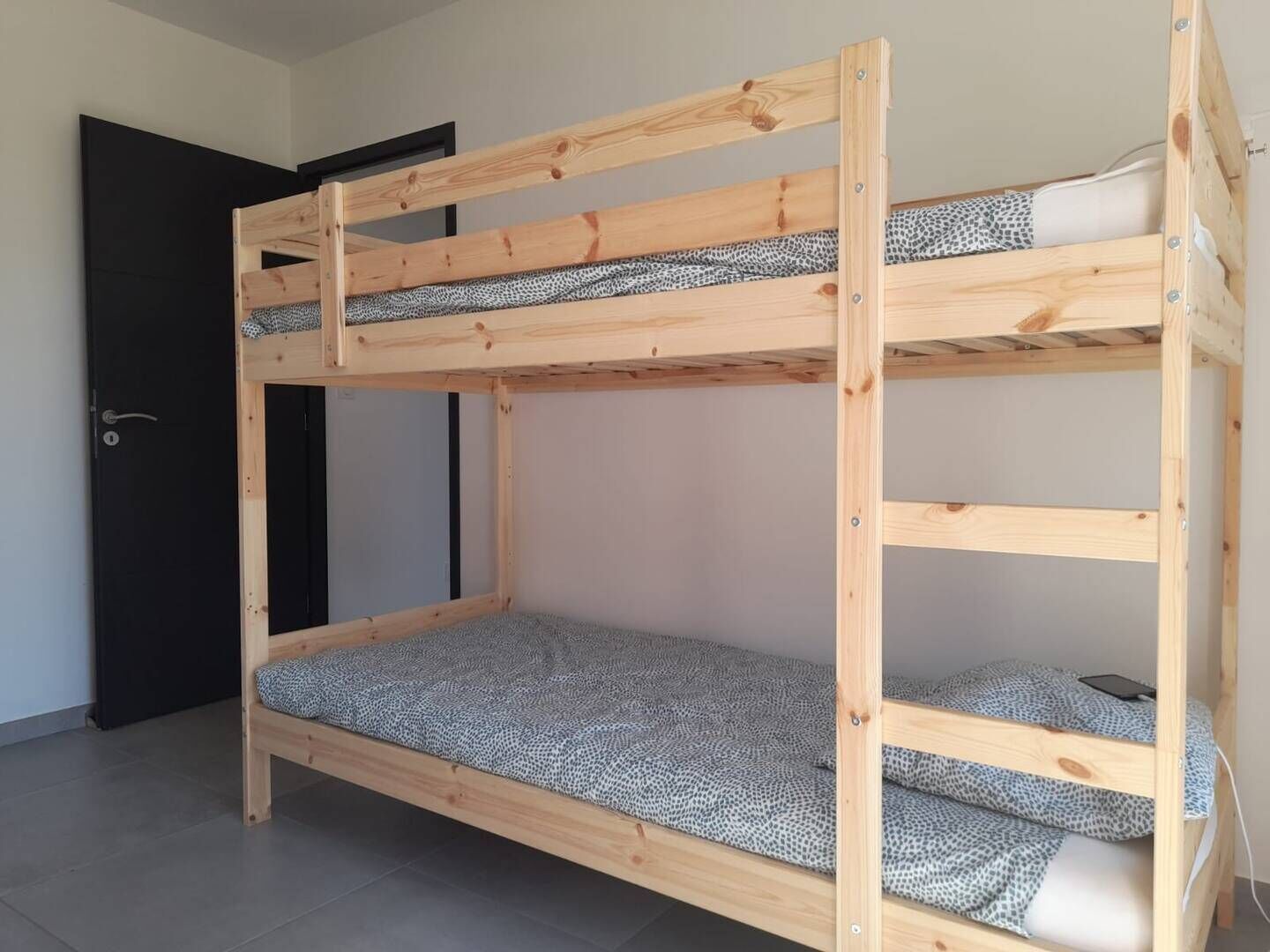 Een stapelbed met houten frame en beddengoed met dessin.