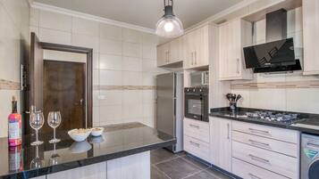 A modern kitchen with a large island, stainless steel appliances, and light wood cabinetry.