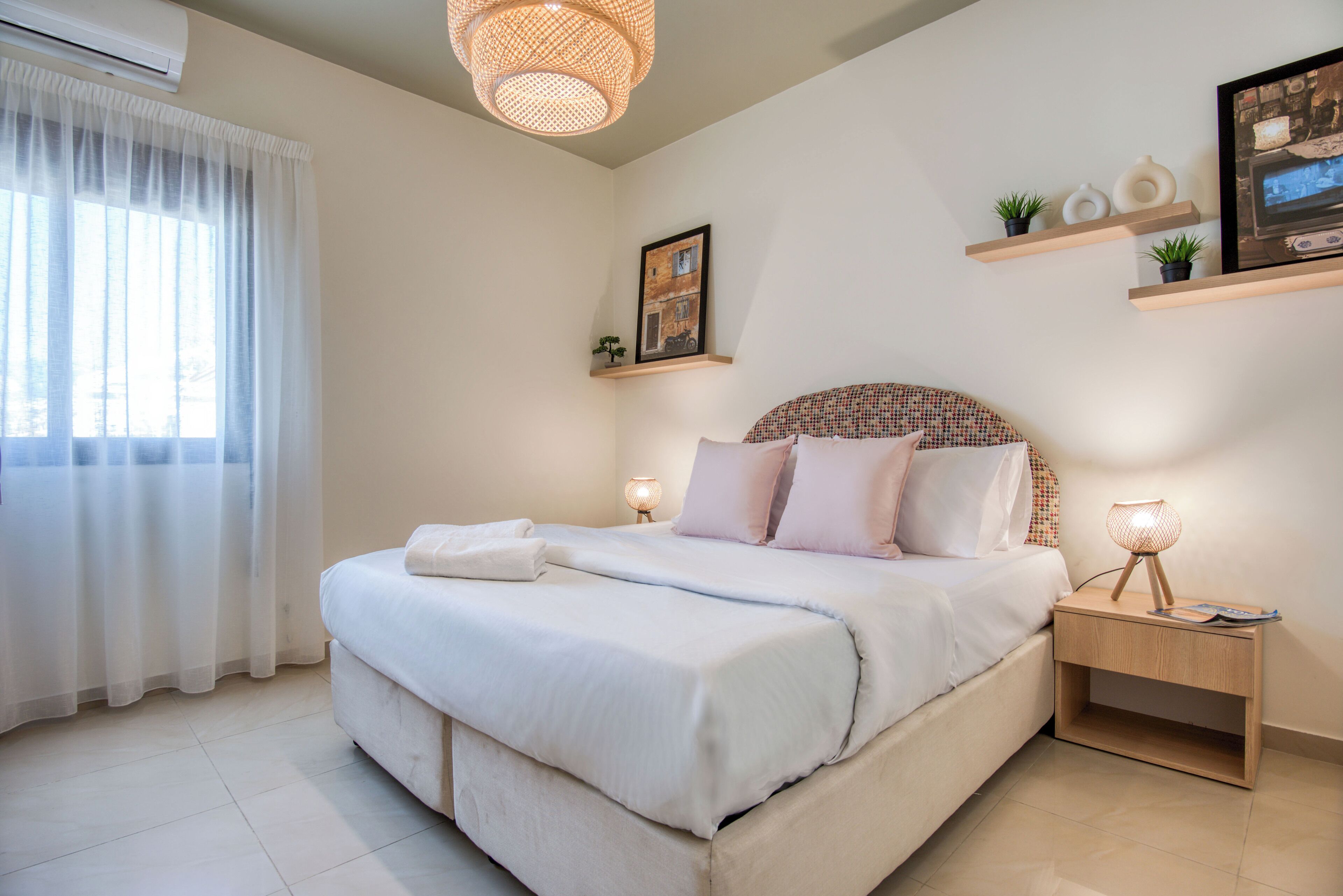 Quarto com cama grande, abajures, mesa de cabeceira e janela com cortinas.