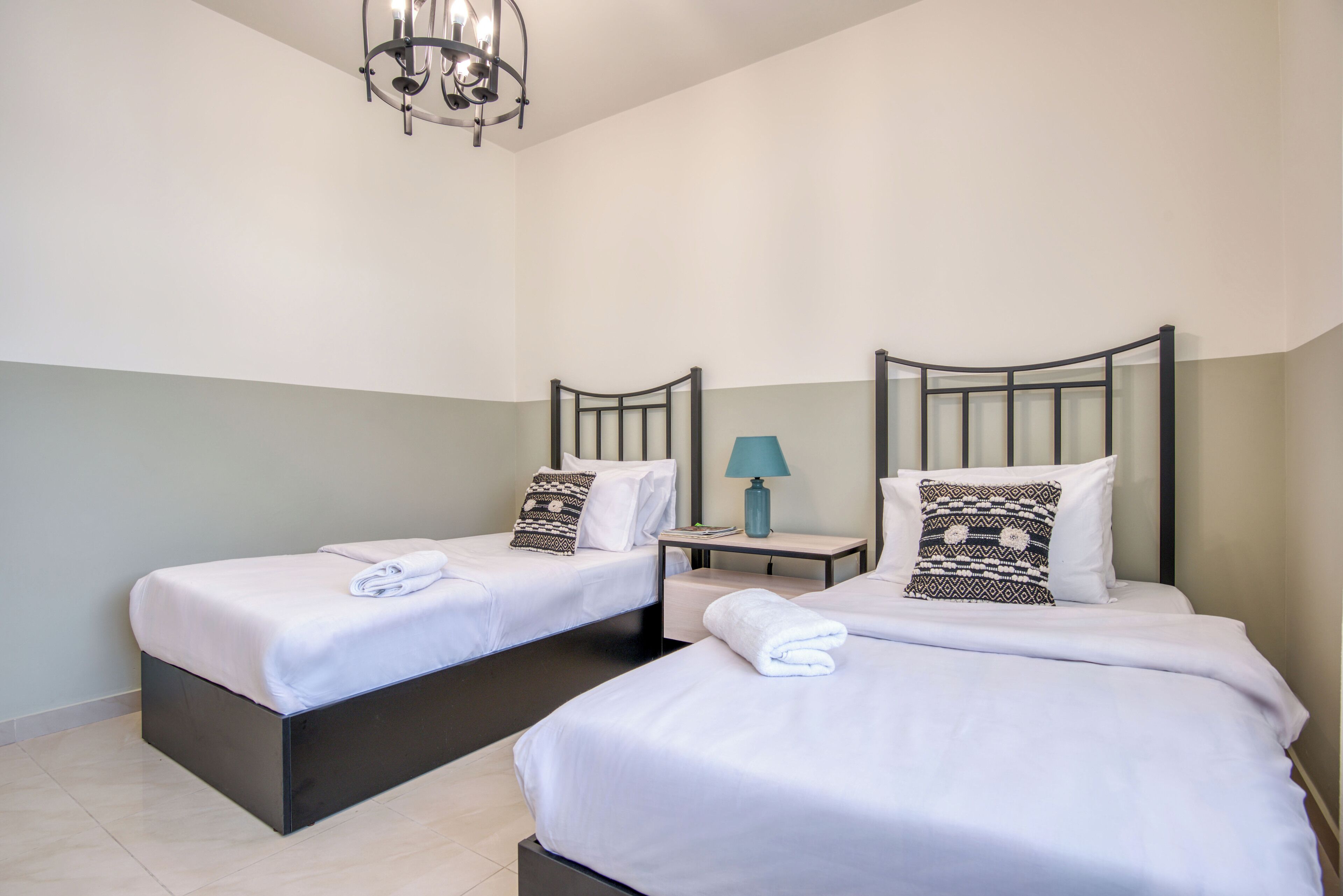Una habitación de hotel con dos camas, una mesita de noche, una lámpara y un candelabro.