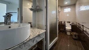 Casa de banho com lavatório branco, cabine de duche em vidro e sanita.