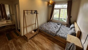 Quarto com cama de padrão de zebra, piso de madeira, janela com cortinas e um balanço de madeira.