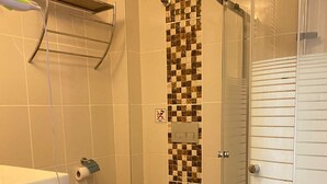 A bathroom with a toilet, a shower, and a sink.