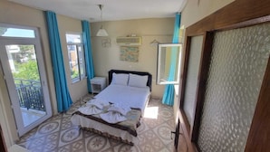 A bedroom with a bed, a window, a door, and a ceiling fan.