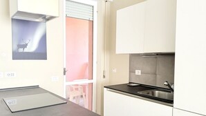 Eine Küche mit schwarzem Arbeitsplatz, weißen Schränken, einer Edelstahl-Spüle und einem kleinen Fenster mit Hirschsilhouette.