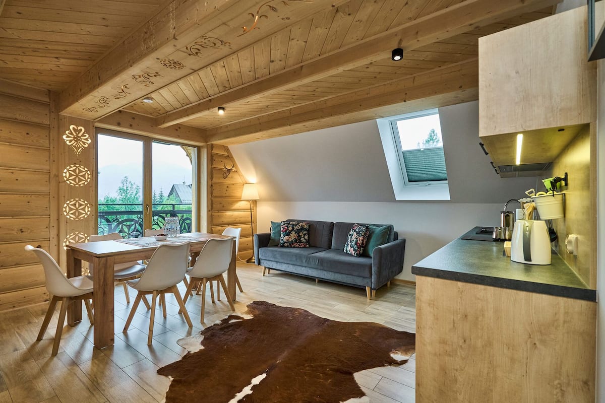 A wooden interior with a dining area, sofa, and kitchen counter.