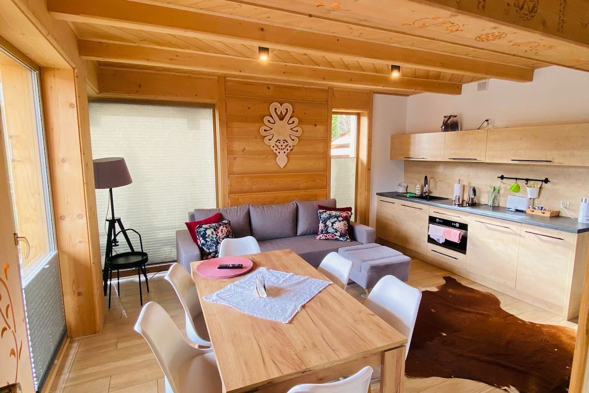 A cozy wooden interior with a dining area, sofa, and kitchen.