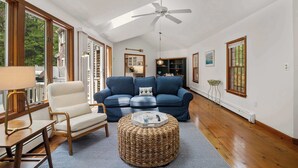 A spacious living room with a ceiling fan, a sofa, a chair, a coffee table, and a view of the kitchen.