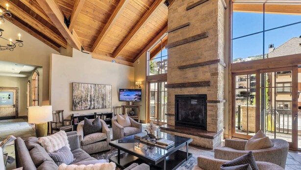 A spacious living room with a fireplace, comfortable seating, a television, and a large window offering a view of the outside.