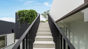 A staircase with black railings leading to a modern building with a glass facade. - Villa Qabalah (Si Sunthon)