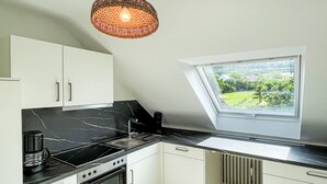 A modern kitchen with white cabinets, a black countertop, a built-in oven, and a window with a view of greenery.
