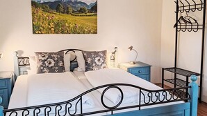 Ein Schlafzimmer mit einem Bett, einem Nachttisch, einer Lampe und einem an der Wand befestigten Regal.