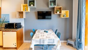 A modern kitchen with a microwave, a dining table with chairs, and built-in shelves with decorative items.