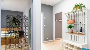 A modern interior with a bed, a decorative metal partition, a white bench with shelves, and a blue chair.