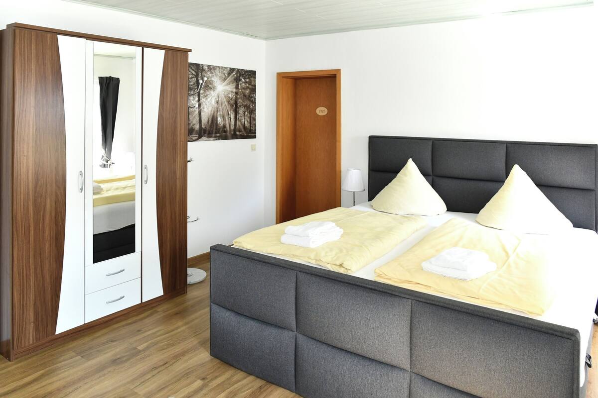 Une chambre à coucher avec un lit, une armoire, une porte et un tableau au mur.