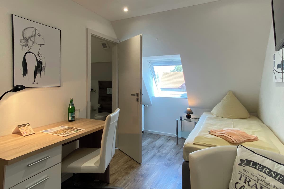 Une chambre à coucher avec un lit, un bureau et une chaise. Il y a une fenêtre donnant sur l’extérieur.