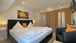 Une chambre d’hôtel avec un grand lit, deux tables de chevet, une chaise, une télévision et une armoire.