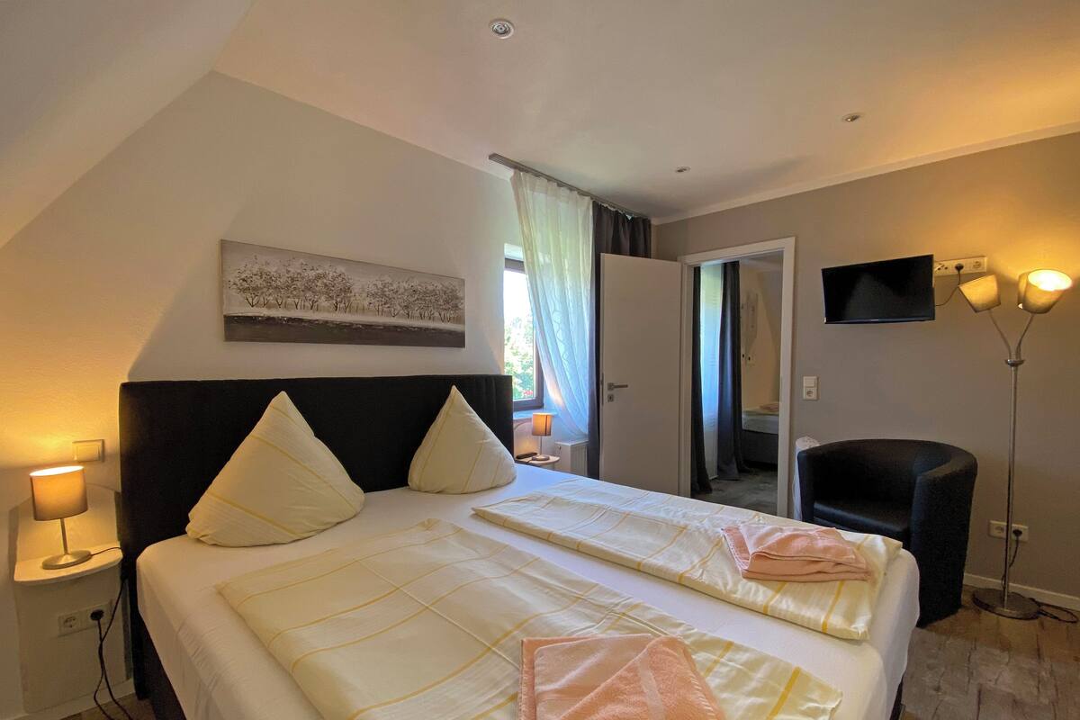 Une chambre d’hôtel avec un grand lit, deux oreillers, une lampe de chevet, un téléviseur et une lampe sur pied.