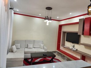 Familienapartment, Stadtblick | Wohnbereich | 24-Zoll-Smart-TV mit Digitalempfang