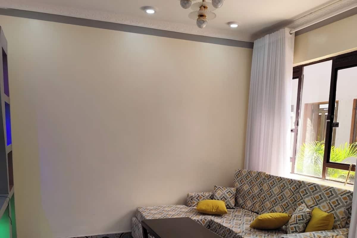 Una sala de estar con sofá, mesa de centro y ventana con cortinas.