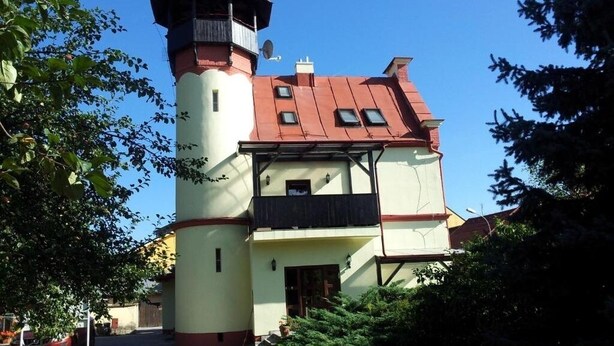 Un edificio de dos pisos con una torre, un balcón y una ventana pequeña.