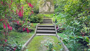A stone staircase leading up to a statue in a lush garden setting. - 1607 Brancion (Paris)
