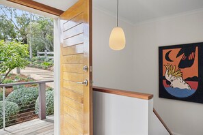 Eine Holztür mit einem modernen Griff, einer Pendelleuchte und einem gerahmten Kunstwerk an der Wand.