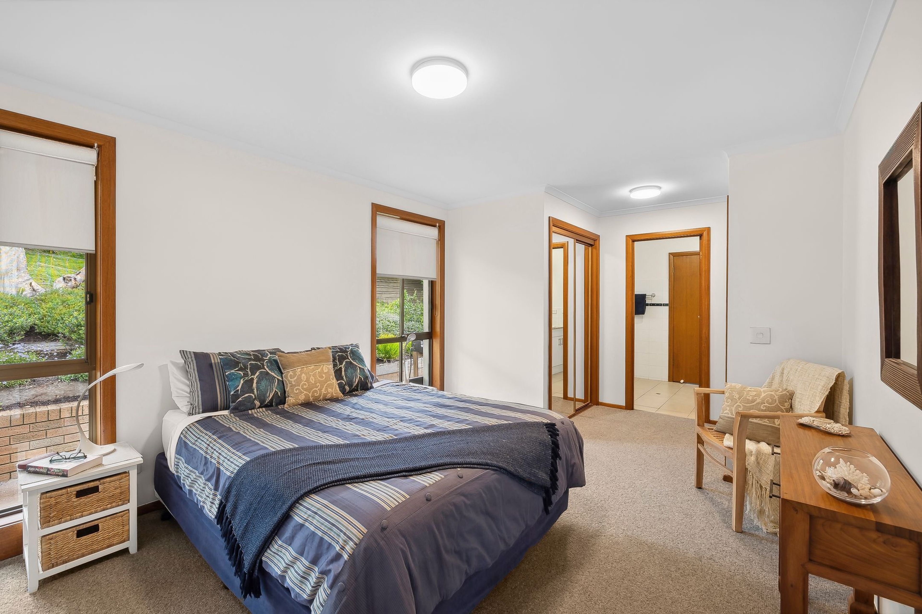A bedroom with a bed, bedside tables, a desk, and a mirror.