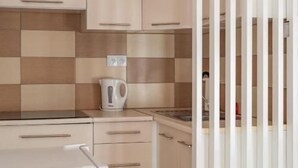 A modern kitchen with light-colored cabinets, a white countertop, and a kettle. - Przytulny apartament KOLEJOVA 12 (Nowy Targ)