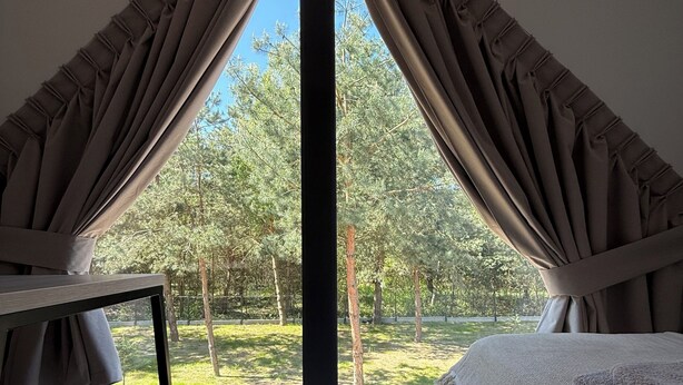 A bedroom with a large window, a bed, and a wooden floor. - Charming 2-bedroom bungalow with AC, WiFi in enchanting Niesulice for 6 person (Niesulice)