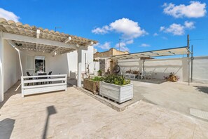 A covered outdoor patio with a white bench, a table, and potted plants. - Villa Benedetta 50m From Beach (Lecce)