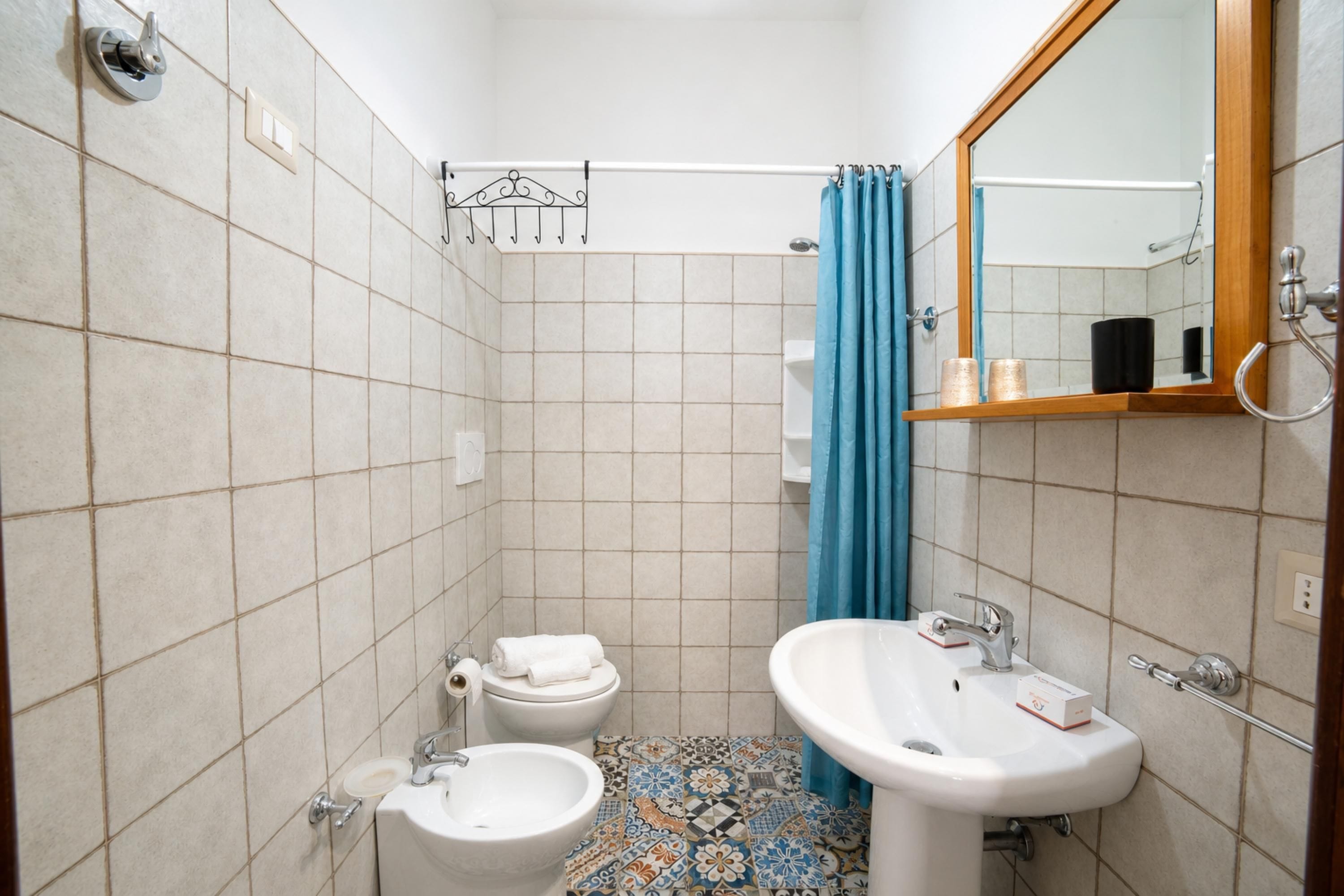 A bathroom with a toilet, bidet, sink, and a mirror.