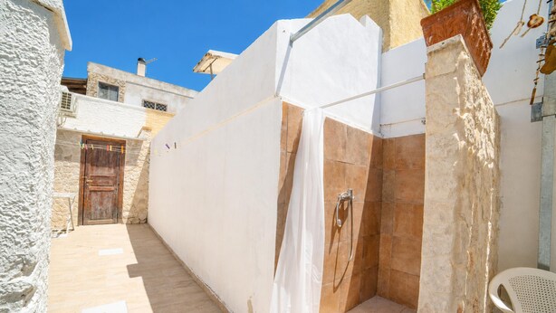 A narrow outdoor corridor with a white wall, a wooden door, and a shower area with a tiled wall. - Villa Benedetta 50m From Beach (Lecce)
