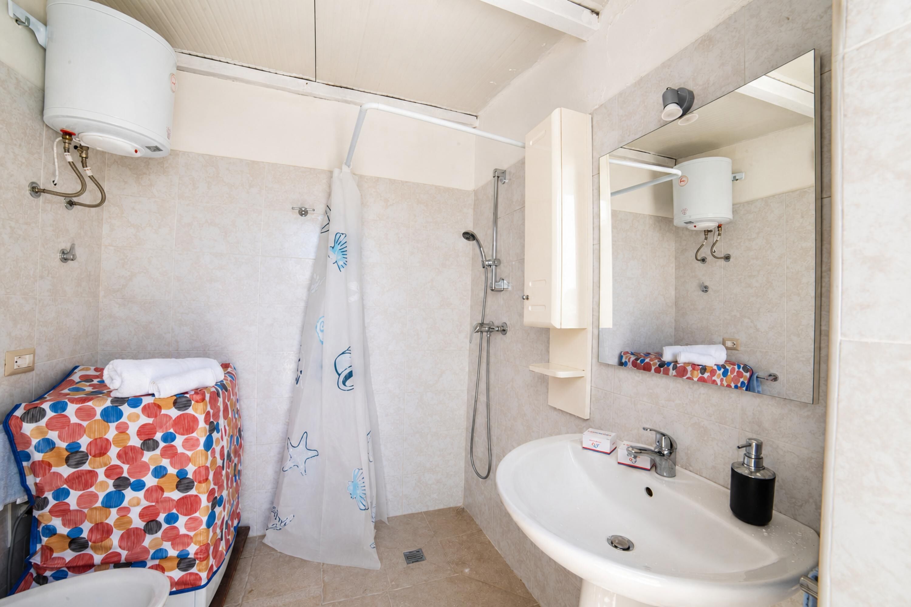 A bathroom with a shower, toilet, sink, and a mirror.