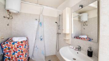 A bathroom with a shower, toilet, sink, and a mirror.